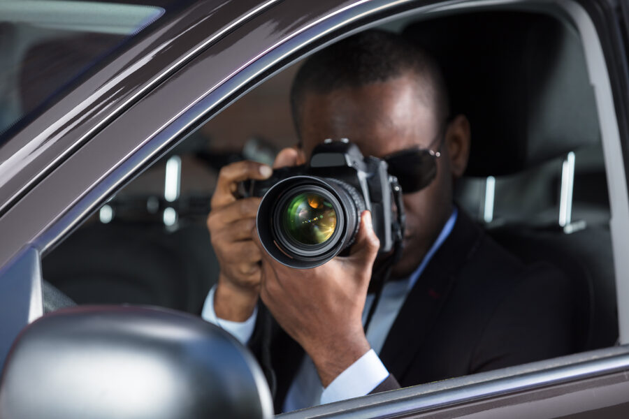 Investigator photographing from a vehicle during surveillance